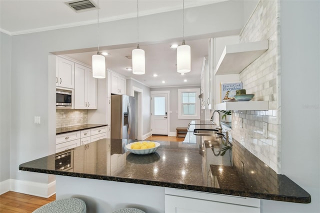 kitchen with visible vents, open shelves, a sink, ornamental molding, and stainless steel appliances