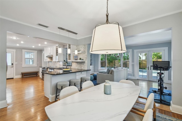 dining space featuring light wood-style flooring, baseboards, ornamental molding, and french doors