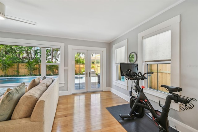 exercise area with ornamental molding, french doors, baseboards, and hardwood / wood-style floors