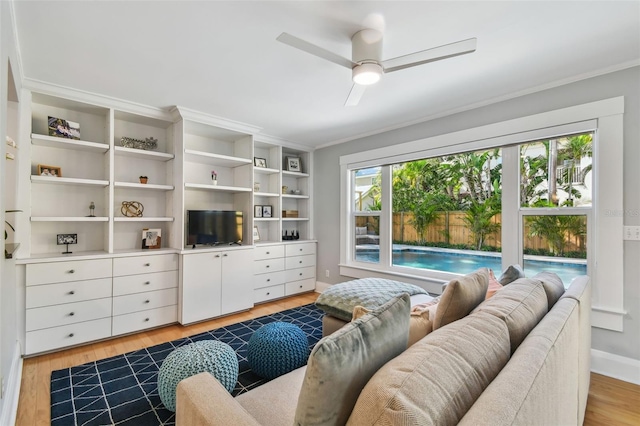 living room with crown molding, ceiling fan, light wood-type flooring, and baseboards