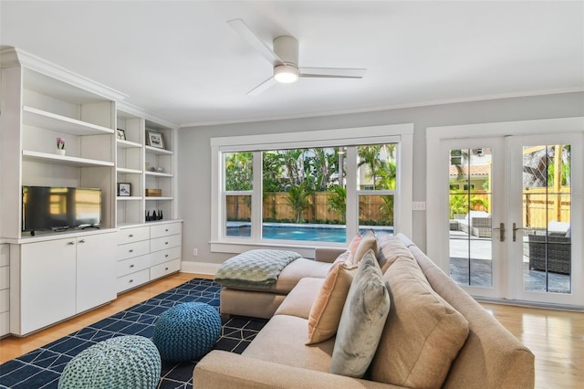 living area with baseboards, ceiling fan, crown molding, french doors, and light wood-style flooring