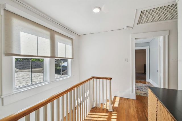 hallway featuring an upstairs landing, wood finished floors, baseboards, and visible vents
