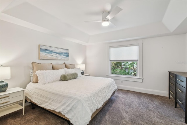 bedroom with baseboards, a tray ceiling, dark carpet, and ceiling fan