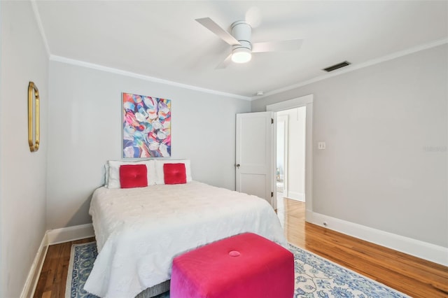 bedroom with crown molding, wood finished floors, and visible vents