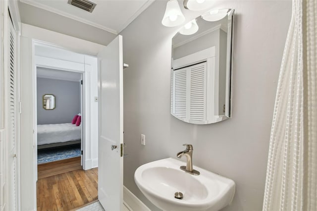 full bath featuring crown molding, wood finished floors, a sink, and visible vents