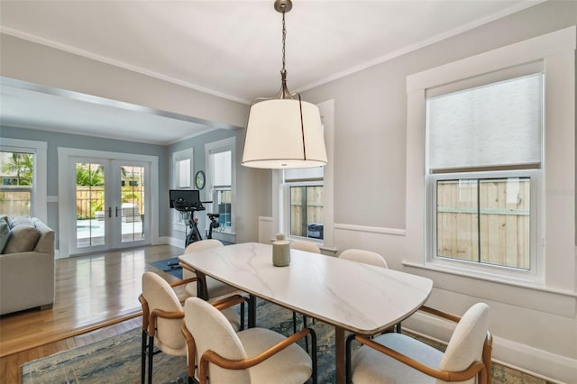 dining space featuring french doors, crown molding, wood finished floors, and baseboards
