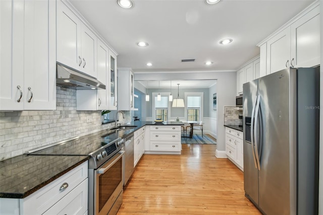 kitchen with white cabinets, a sink, a peninsula, under cabinet range hood, and stainless steel appliances