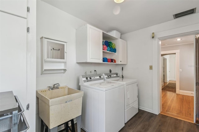washroom with visible vents, washer and clothes dryer, cabinet space, dark wood finished floors, and a sink
