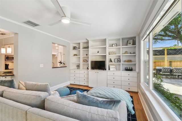 living area featuring crown molding, a ceiling fan, visible vents, light wood finished floors, and baseboards