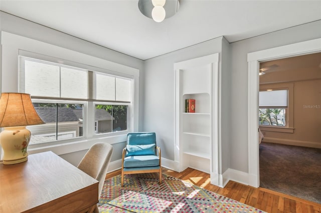 living area with baseboards, a ceiling fan, and wood finished floors