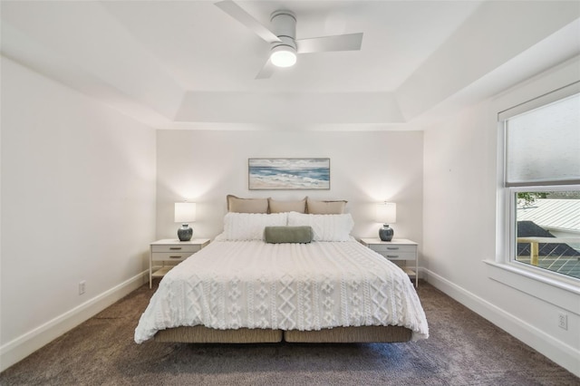 bedroom featuring dark colored carpet, baseboards, a ceiling fan, and a raised ceiling