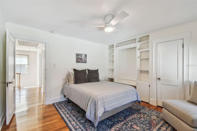 bedroom featuring visible vents, baseboards, ceiling fan, attic access, and wood finished floors