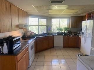 kitchen featuring a paneled ceiling, white appliances, visible vents, light tile patterned flooring, and brown cabinets