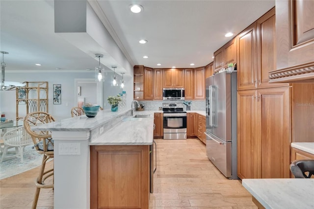kitchen featuring open shelves, a sink, appliances with stainless steel finishes, a kitchen bar, and brown cabinets