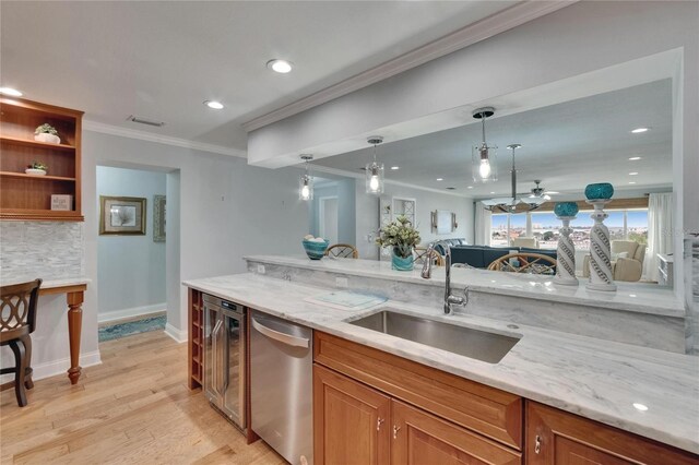 kitchen with stainless steel dishwasher, ornamental molding, a ceiling fan, a sink, and light wood finished floors