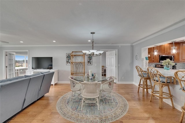 dining room with ornamental molding, baseboards, light wood finished floors, and a chandelier