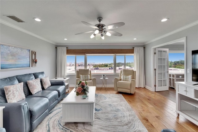 living room featuring plenty of natural light, light wood finished floors, visible vents, and a ceiling fan