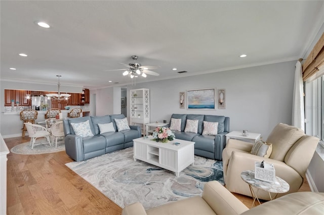 living area with recessed lighting, light wood finished floors, ceiling fan with notable chandelier, and crown molding