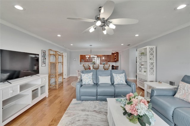 living room featuring baseboards, recessed lighting, light wood-style flooring, crown molding, and ceiling fan with notable chandelier