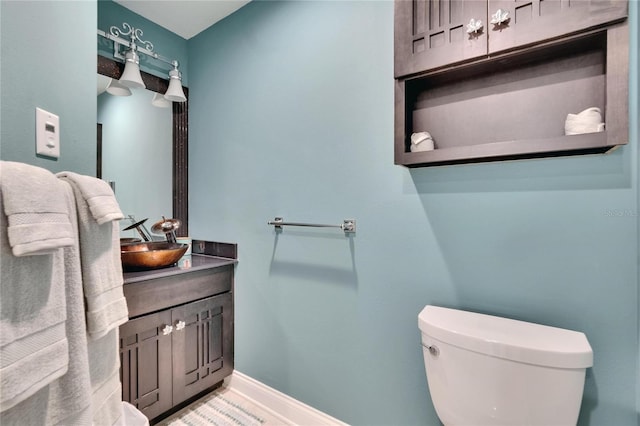 half bath with toilet, vanity, and baseboards