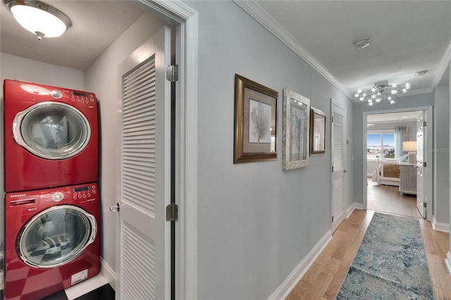 laundry area with baseboards, stacked washer and dryer, ornamental molding, laundry area, and wood finished floors