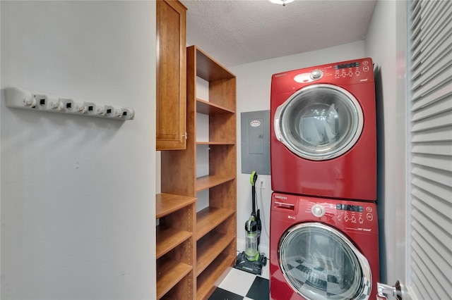 clothes washing area with stacked washer and dryer, tile patterned floors, cabinet space, and a textured ceiling