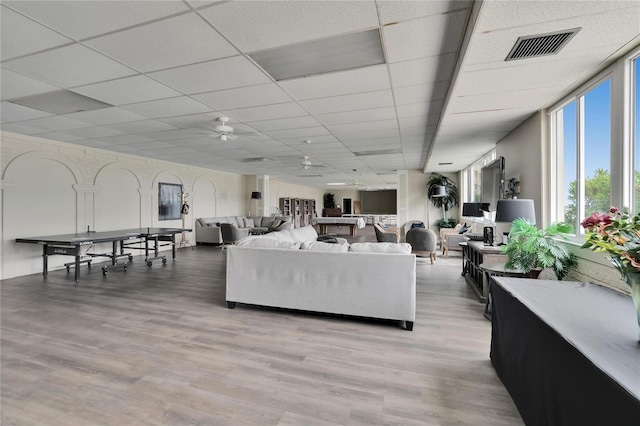 living room featuring visible vents, light wood-type flooring, a ceiling fan, and a drop ceiling