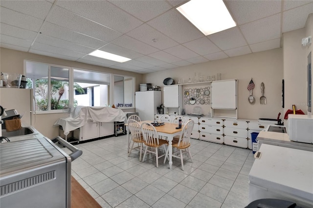 dining room featuring a drop ceiling and light tile patterned flooring
