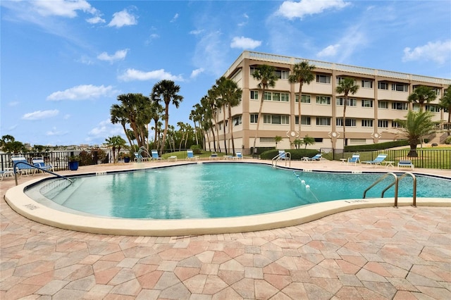 pool with a patio area and fence