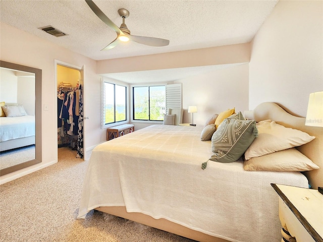 1500 Sunset Rd Unit C7, Tarpon Springs, FL 34689 - bedroom featuring a walk in closet, light carpet, a closet, ceiling fan, and a textured ceiling