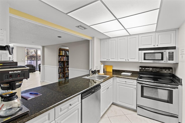 220 Belleview Blvd Unit 104, Belleair, FL 33756 - kitchen with stainless steel appliances, light tile patterned floors, white cabinets, dark stone countertops, and open floor plan