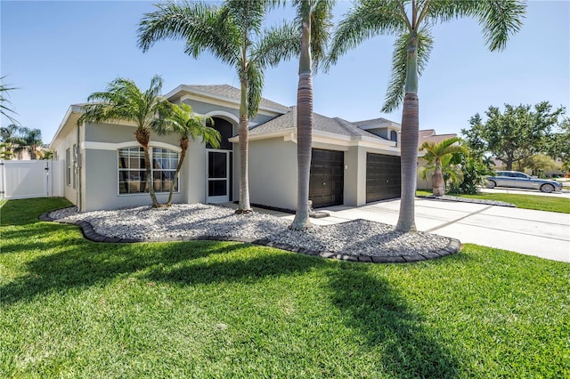 view of front of property featuring stucco siding, a front yard, fence, an attached garage, and concrete driveway