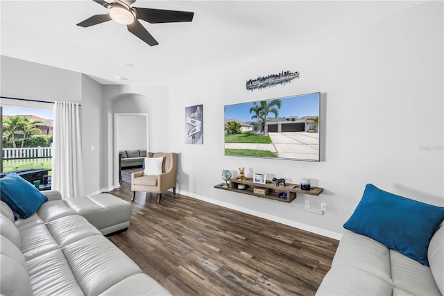 living area featuring arched walkways, wood finished floors, baseboards, and a ceiling fan