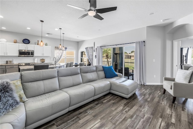 living room featuring baseboards, arched walkways, ceiling fan, dark wood finished floors, and recessed lighting