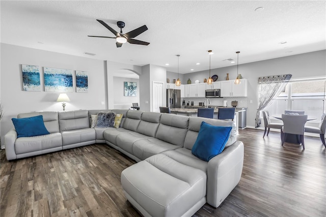 living area featuring arched walkways, ceiling fan, dark wood finished floors, and recessed lighting