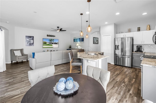 dining area with arched walkways, a ceiling fan, recessed lighting, baseboards, and dark wood-style floors
