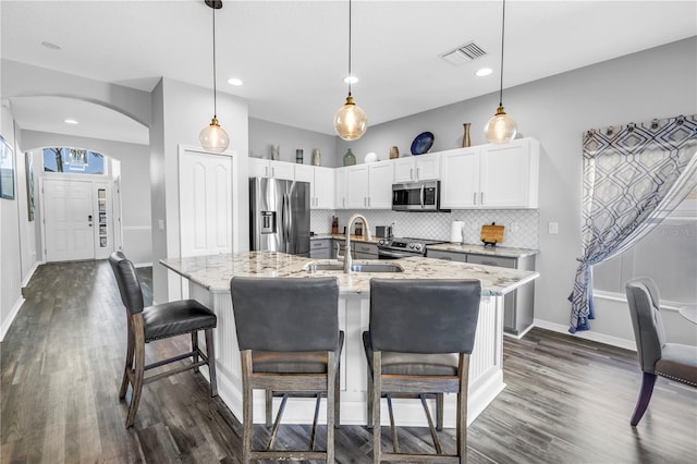 kitchen with a sink, dark wood finished floors, visible vents, and stainless steel appliances