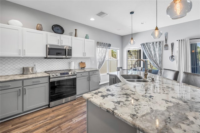 kitchen with dark wood-type flooring, visible vents, gray cabinets, a sink, and stainless steel appliances