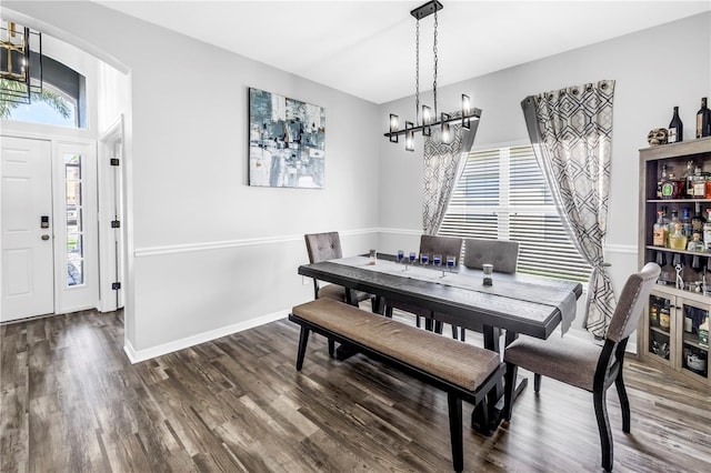 dining space with baseboards, arched walkways, a notable chandelier, and wood finished floors