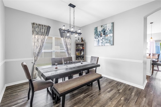 dining room with baseboards, arched walkways, a chandelier, and wood finished floors