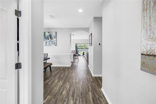 corridor featuring visible vents, baseboards, arched walkways, dark wood-style floors, and recessed lighting