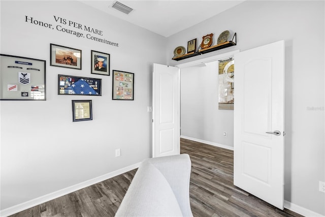 corridor featuring visible vents, baseboards, and wood finished floors