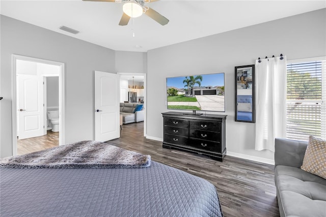 bedroom with baseboards, ensuite bath, a ceiling fan, visible vents, and wood finished floors