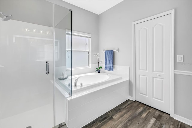 full bath with a bath, a shower stall, and wood finished floors