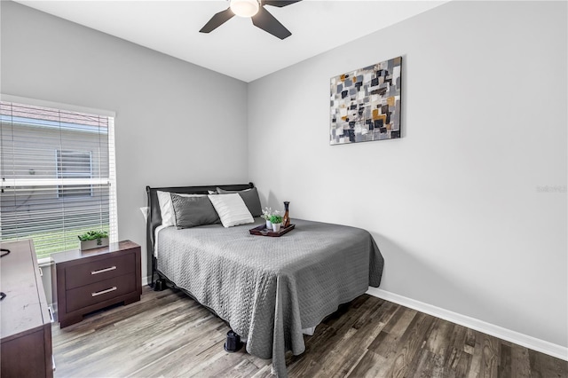 bedroom with wood finished floors, ceiling fan, baseboards, and multiple windows