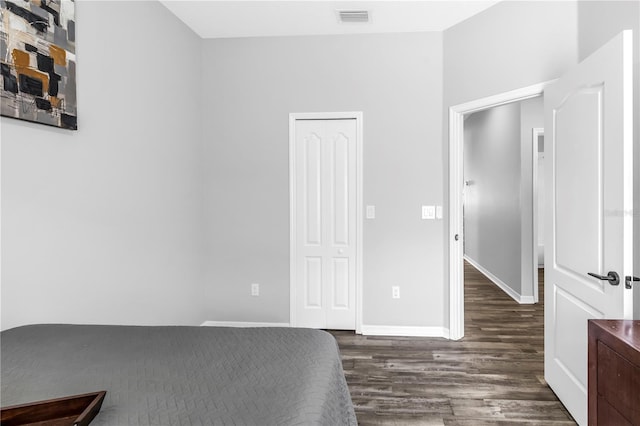 bedroom with a closet, visible vents, baseboards, and wood finished floors