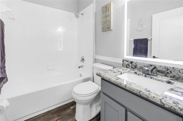 bathroom with toilet, wood finished floors, vanity, and washtub / shower combination