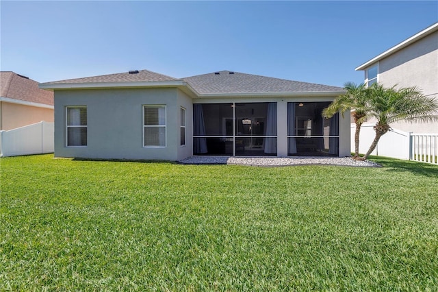 rear view of property with stucco siding, fence private yard, and a lawn