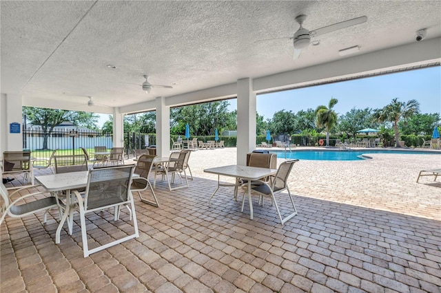 view of patio with a ceiling fan, a community pool, and fence