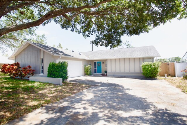 ranch-style house featuring board and batten siding, an attached garage, concrete driveway, and fence